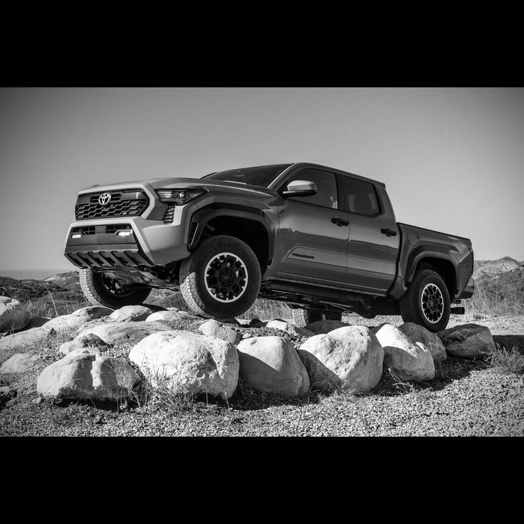 2024 Toyota Tacoma offroading on rocks in black and white